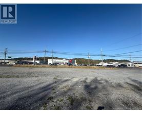 A gravel lot with a building in the background and power lines above.
