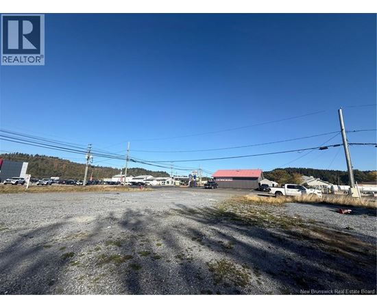 A gravel lot with a building in the background and a sign that says REALTOR.