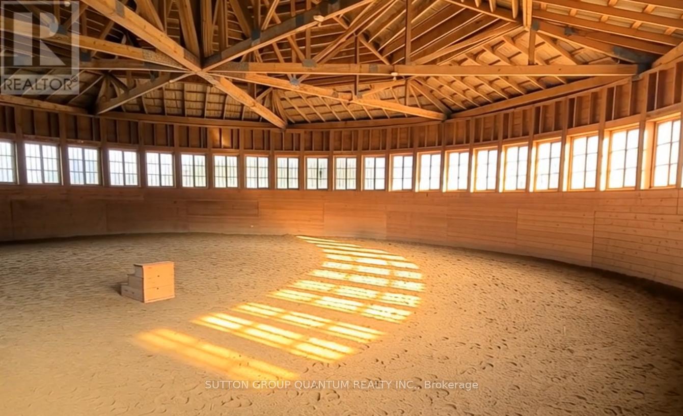 A large, empty room with wooden beams and windows letting in sunlight.