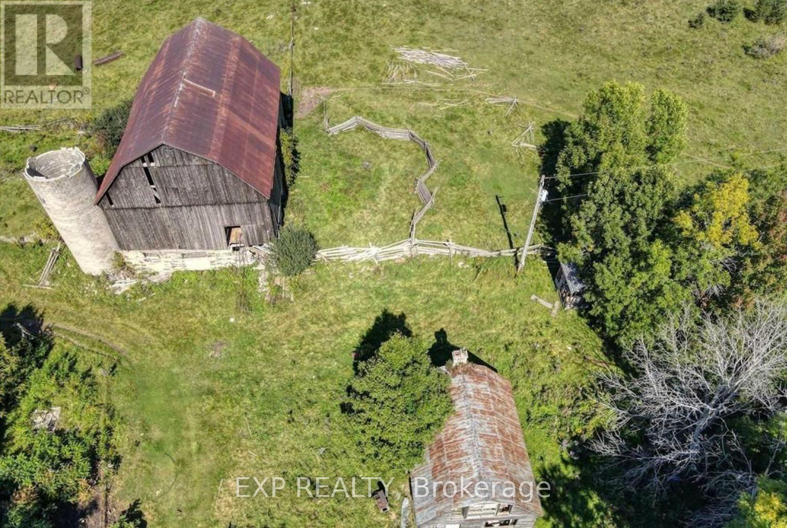 An old barn with a rusted roof sits in a grassy field.