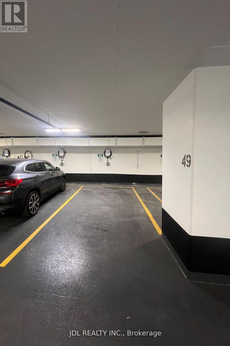A car is parked in a parking garage with yellow lines on the floor.