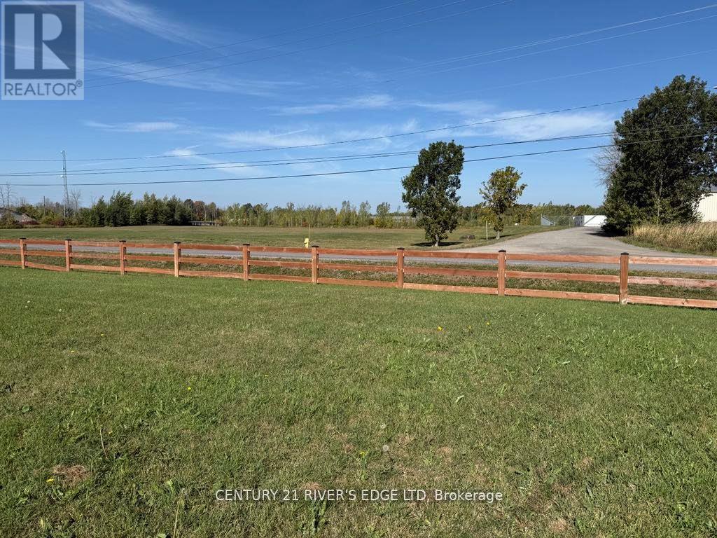 A fenced grassy area with a sign that says Century 21 River's Edge Ltd Brokerage.