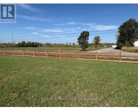 A fenced grassy area with a sign that says Century 21 River's Edge Ltd Brokerage.