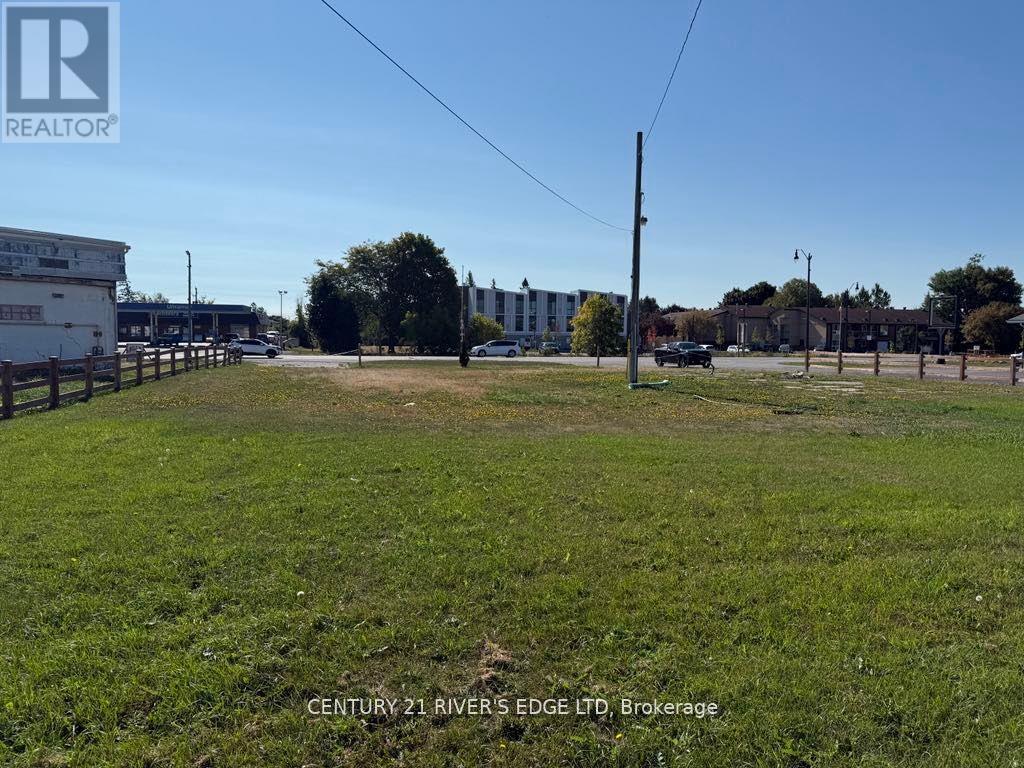 A grassy field with a building in the background and a sign that says Century 21 River Edge LTD Brokerage.