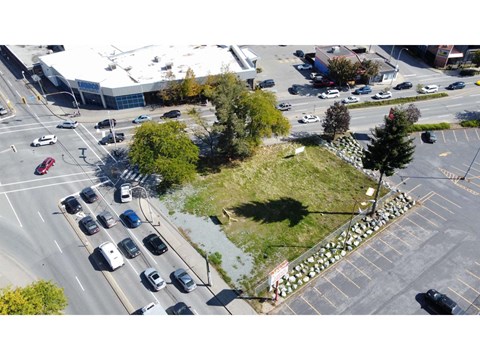 A busy intersection with cars and a green hill in the middle.