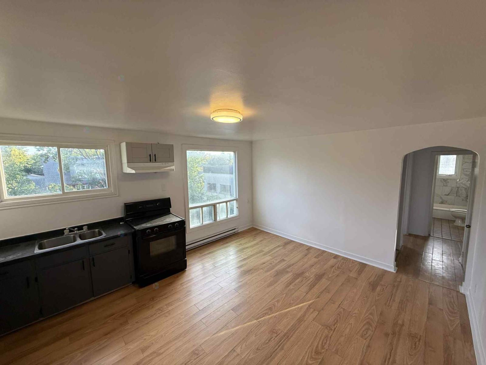 A kitchen with black appliances and wooden floors.
