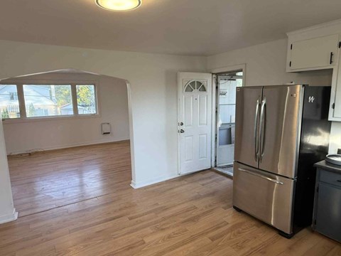 A kitchen with a refrigerator and wooden floors.