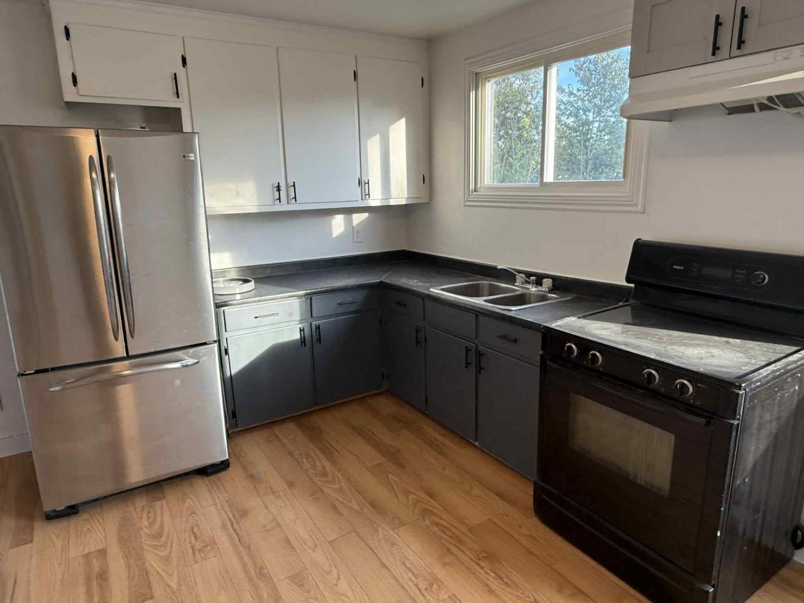 A kitchen with a stainless steel refrigerator, oven, and cabinets.