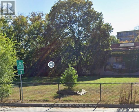 A green sign with a white bicycle symbol and the words "RE/MAX HALLMARK REALTY GROUP Brokerage" is on a fence.