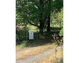 A sign in front of a tree in a field.
