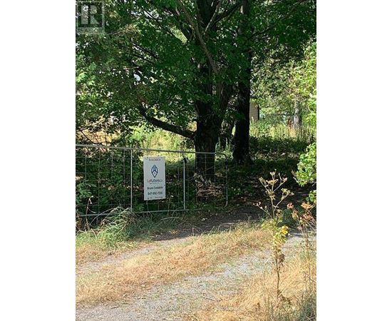 A sign in front of a tree in a field.