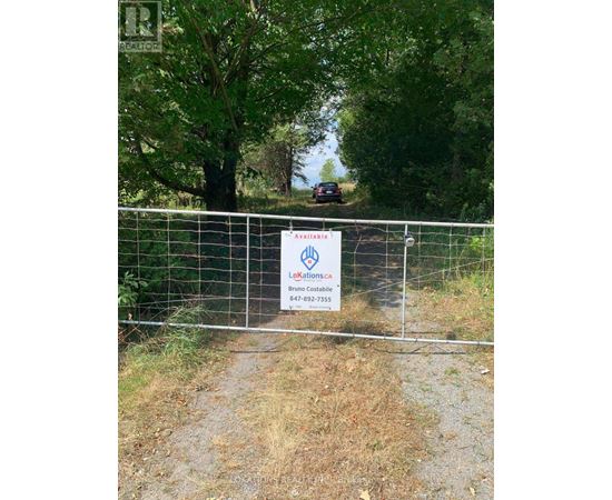 A sign for Avaxilaria is posted on a fence in front of a wooded area.
