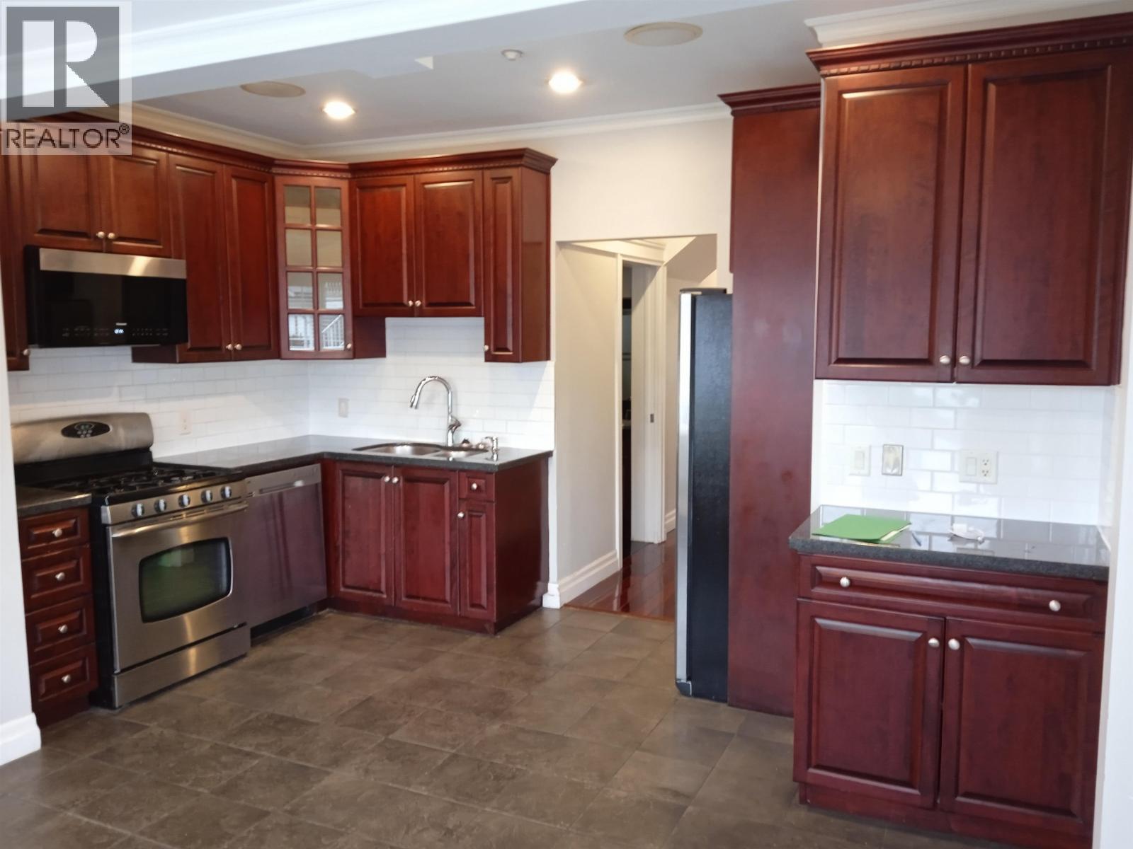 A kitchen with dark wood cabinets and a stainless steel oven.