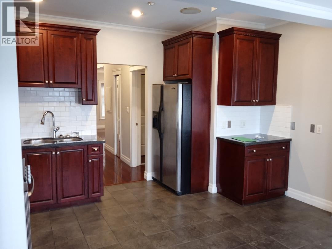 A kitchen with dark wood cabinets and a stainless steel refrigerator.