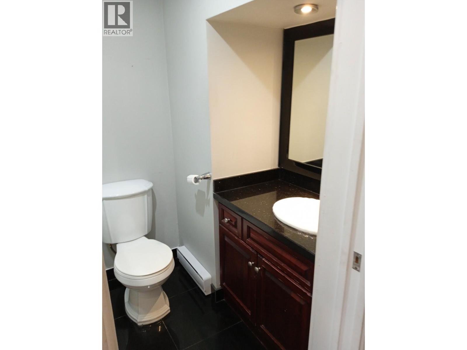 A white toilet sits in a bathroom next to a sink.