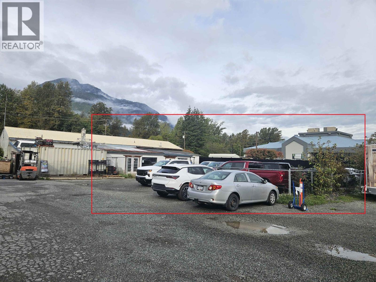A parking lot with cars and a mountain in the background.