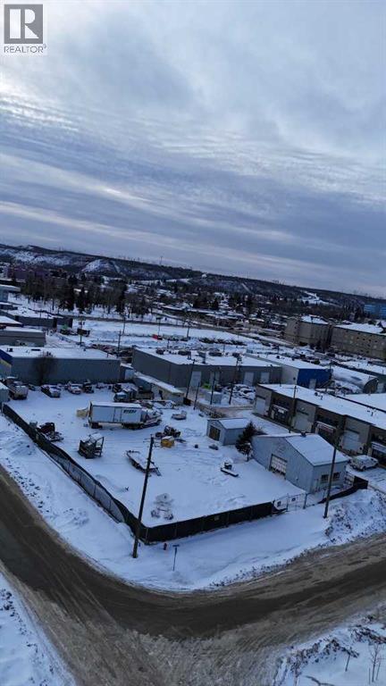 A snowy landscape with a building and a fence in the foreground.