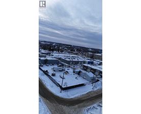 A snowy landscape with a building and a fence in the foreground.