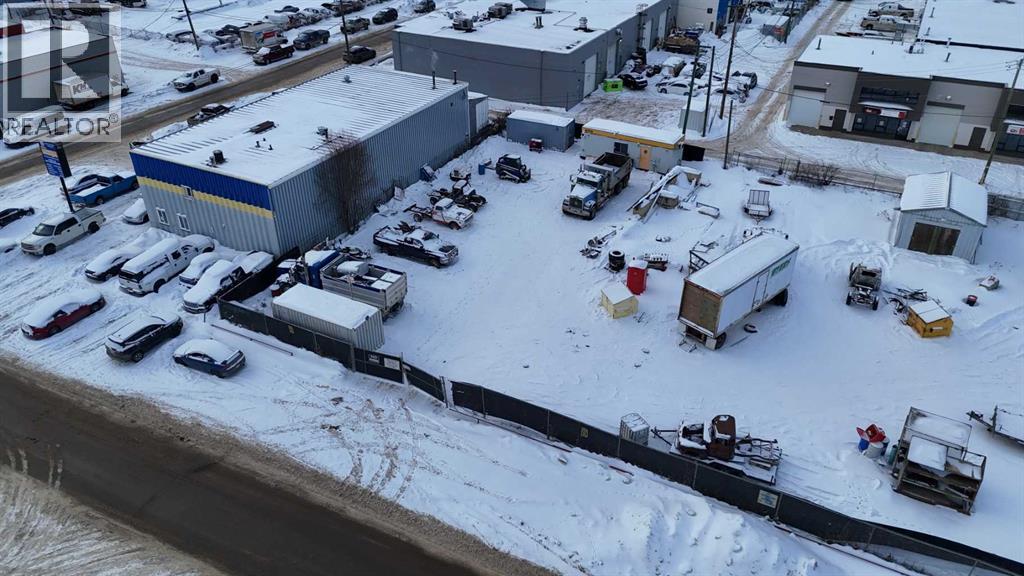 A parking lot with several cars and trucks is surrounded by snow.