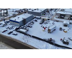 A parking lot with several cars and trucks is surrounded by snow.