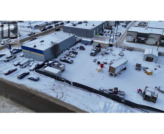 A parking lot with several cars and trucks is surrounded by snow.