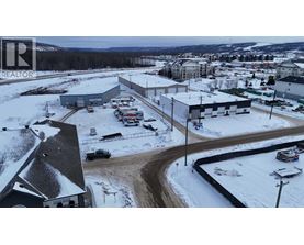 A snowy landscape with a building and cars parked outside.