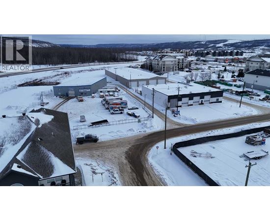 A snowy landscape with a building and cars parked outside.