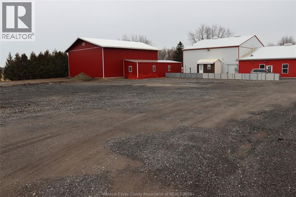 A red barn with a white one behind it, both with a grey roof, stand in a field.