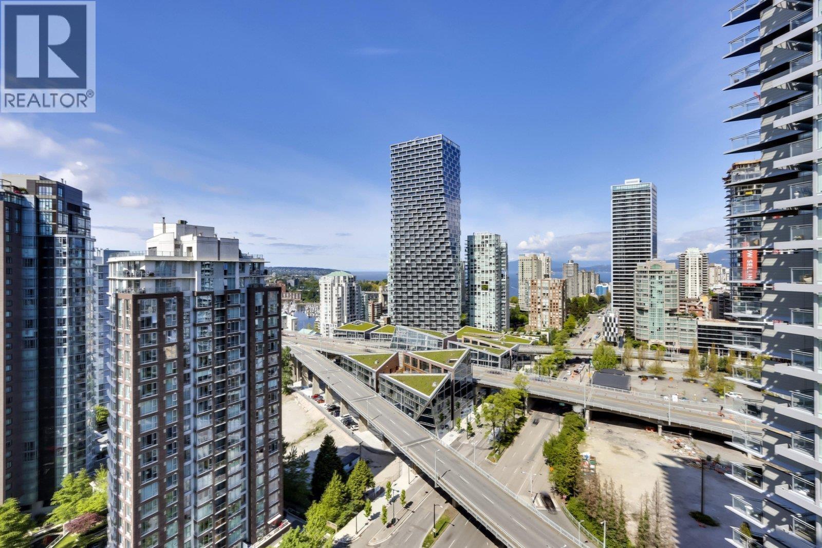 A cityscape with a clear blue sky and a highway in the foreground.