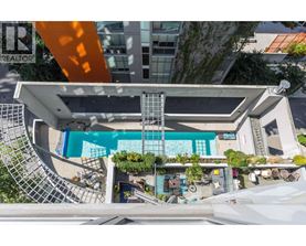 A swimming pool is surrounded by a white building and a metal staircase.
