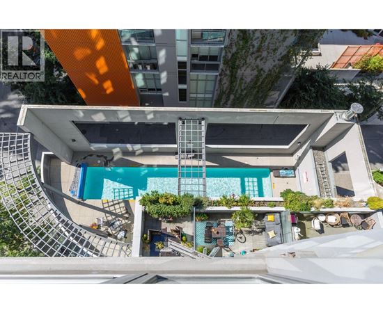 A swimming pool is surrounded by a white building and a metal staircase.