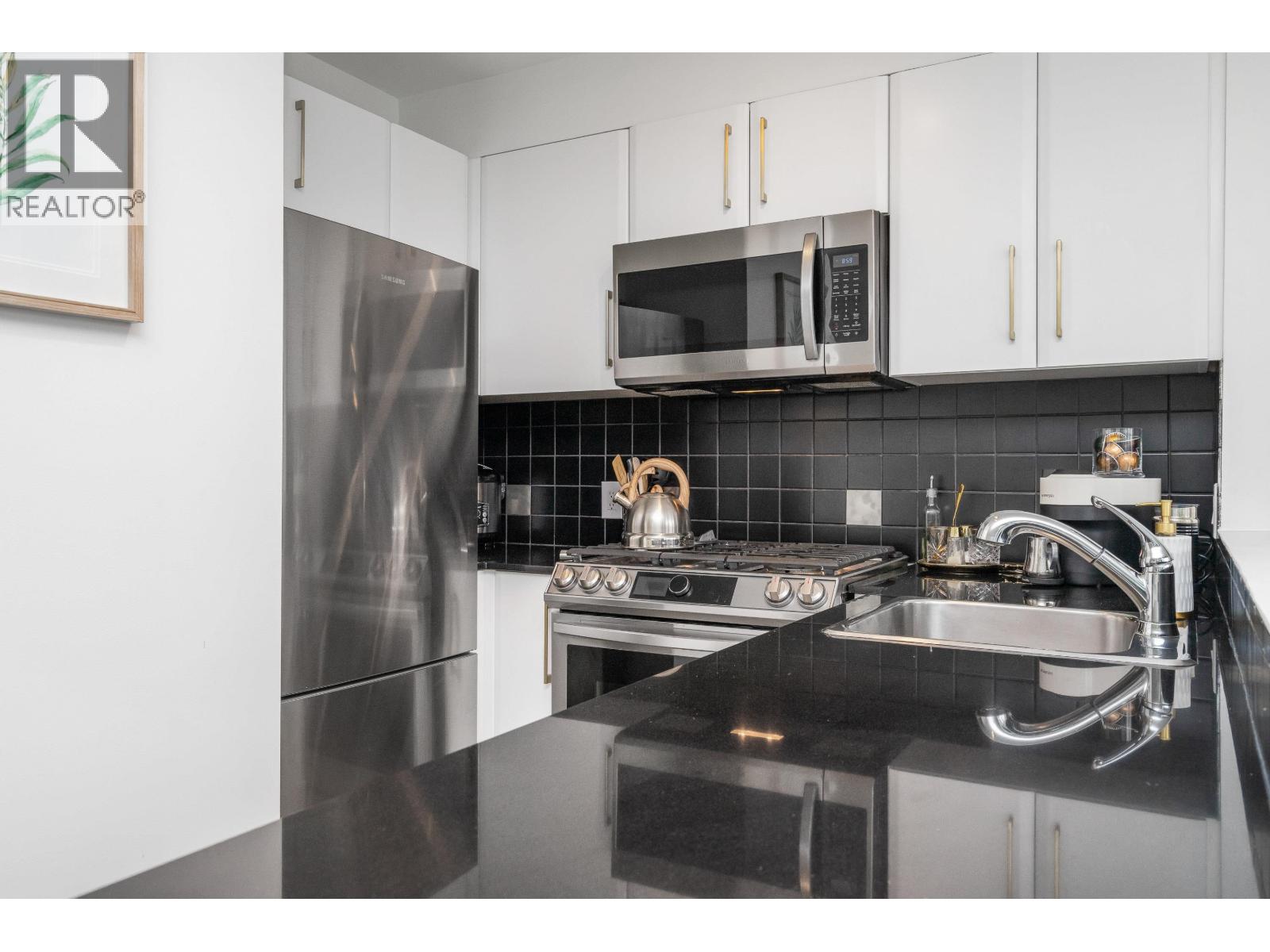A modern kitchen with a stainless steel refrigerator and microwave.