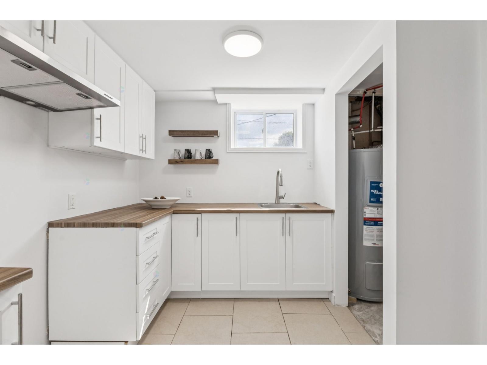 A kitchen with white cabinets and a wooden countertop.