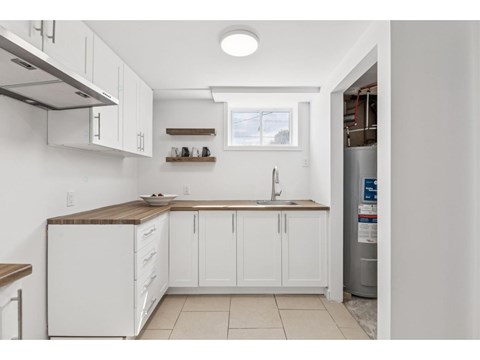 A kitchen with white cabinets and a wooden countertop.