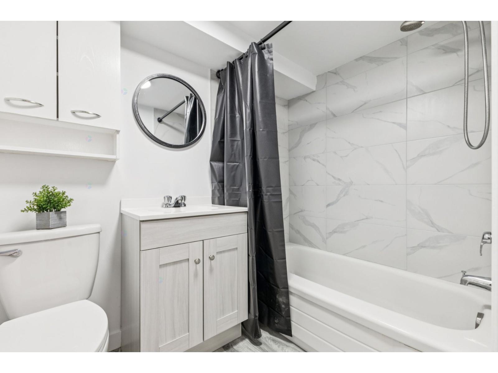 A bathroom with a white tub, toilet, and sink.