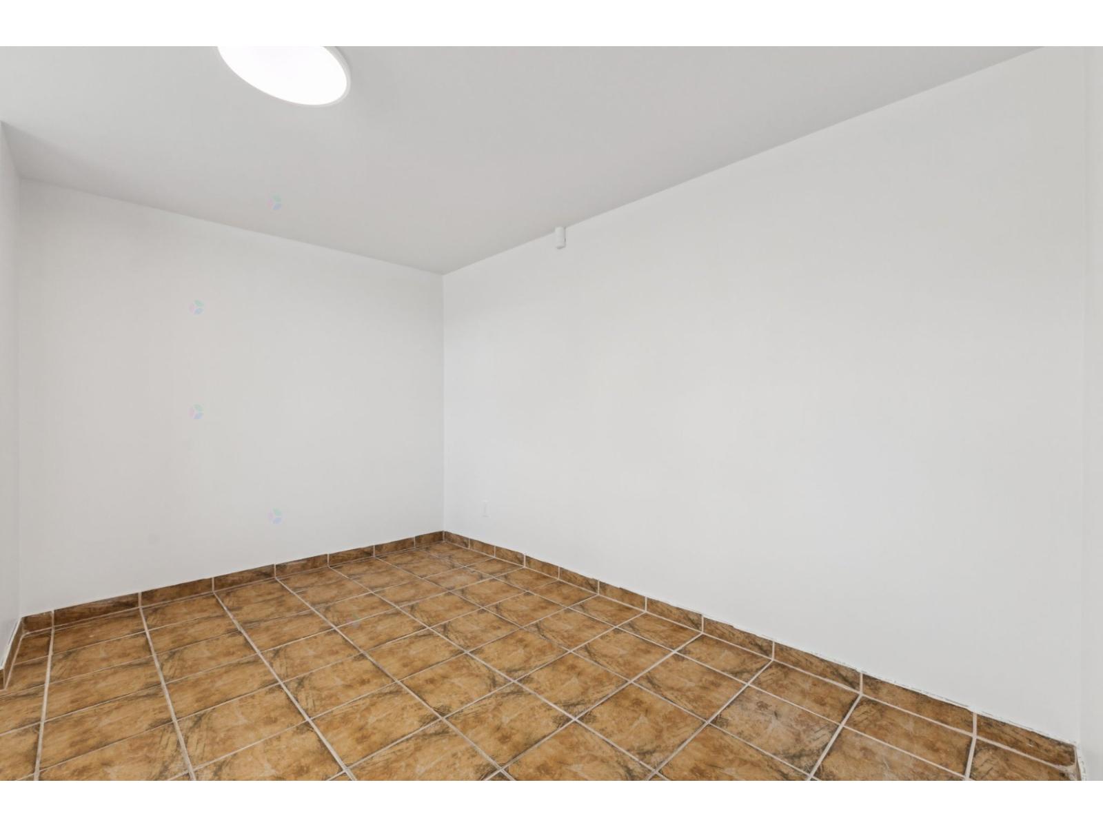 A room with a brown tile floor and white walls.