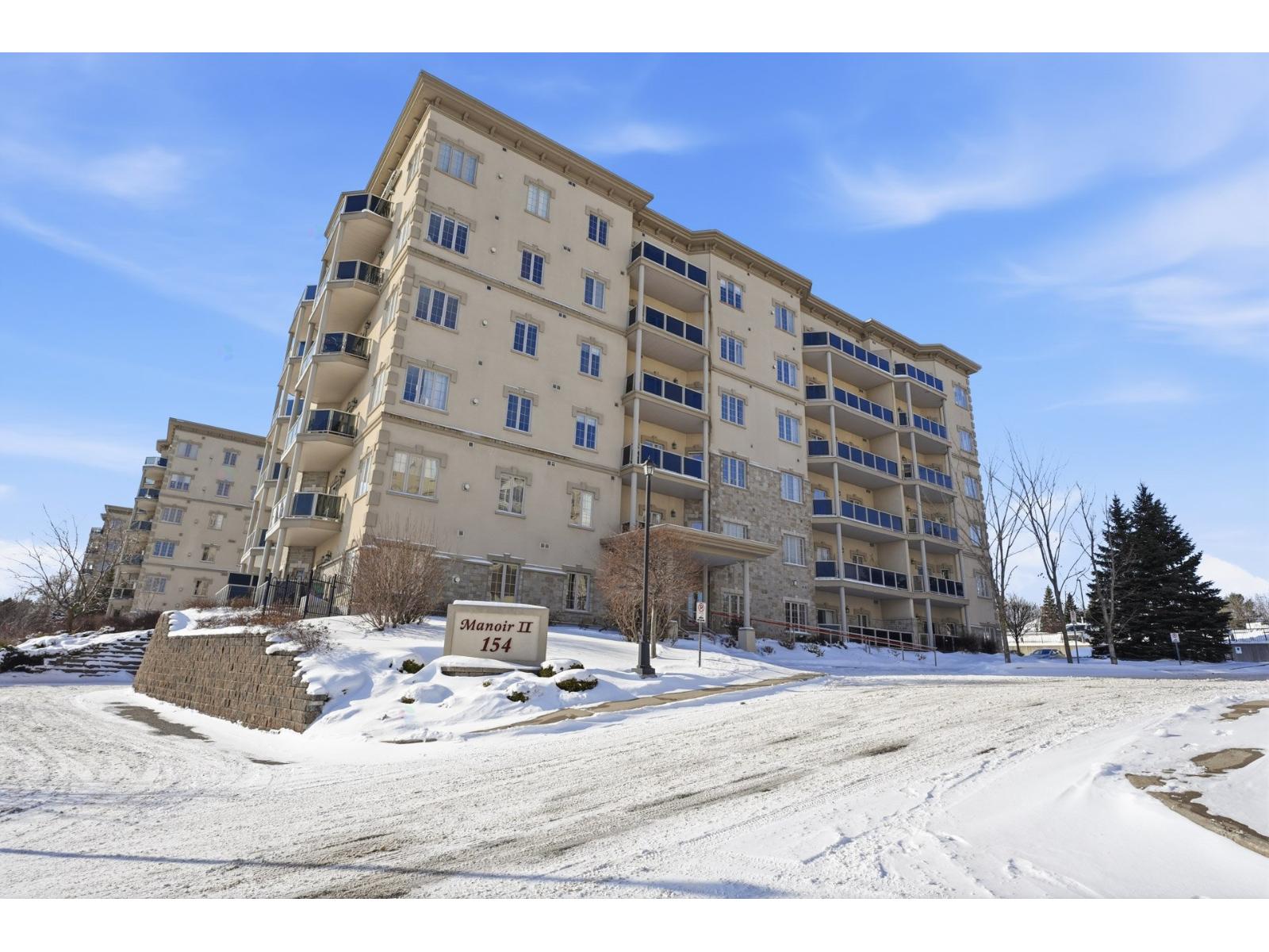 A large beige apartment building with a sign that reads "Monroe 11 154" in front of it.