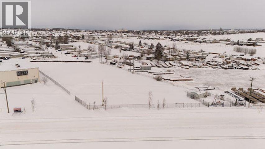 A snowy landscape with a building and a fence in the foreground.