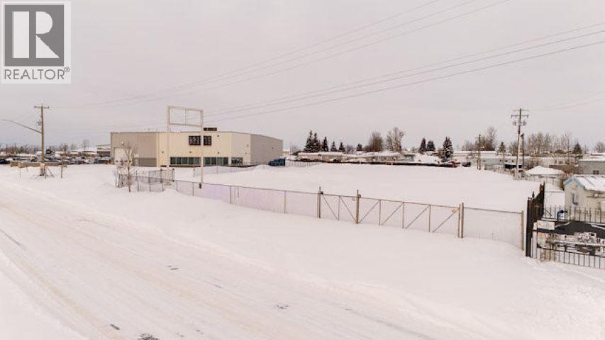 A snowy landscape with a building and a fence in the foreground.