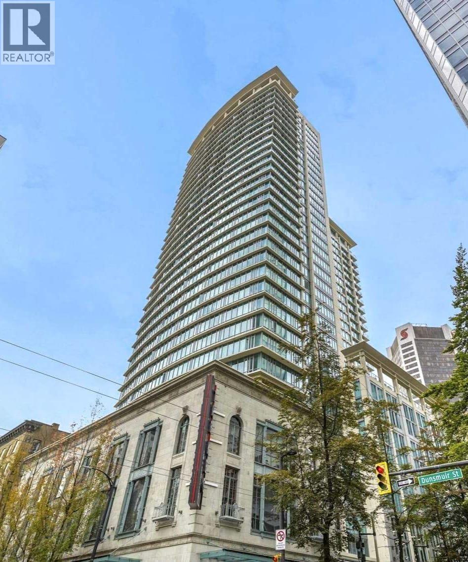 A tall building with a curved top is situated next to a building with a flat top.