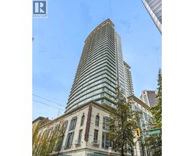 A tall building with a curved top is situated next to a building with a flat top.