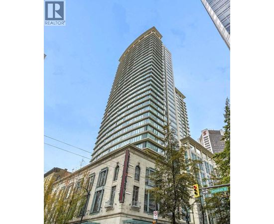A tall building with a curved top is situated next to a building with a flat top.