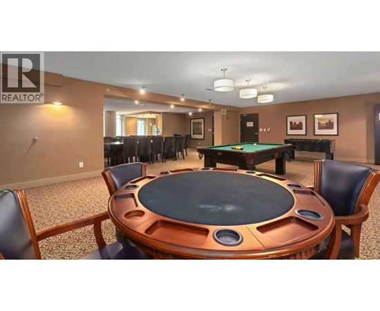 A pool table in a room with a brown table and chairs.