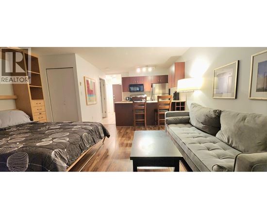 A bedroom with a bed, a couch, and a coffee table.