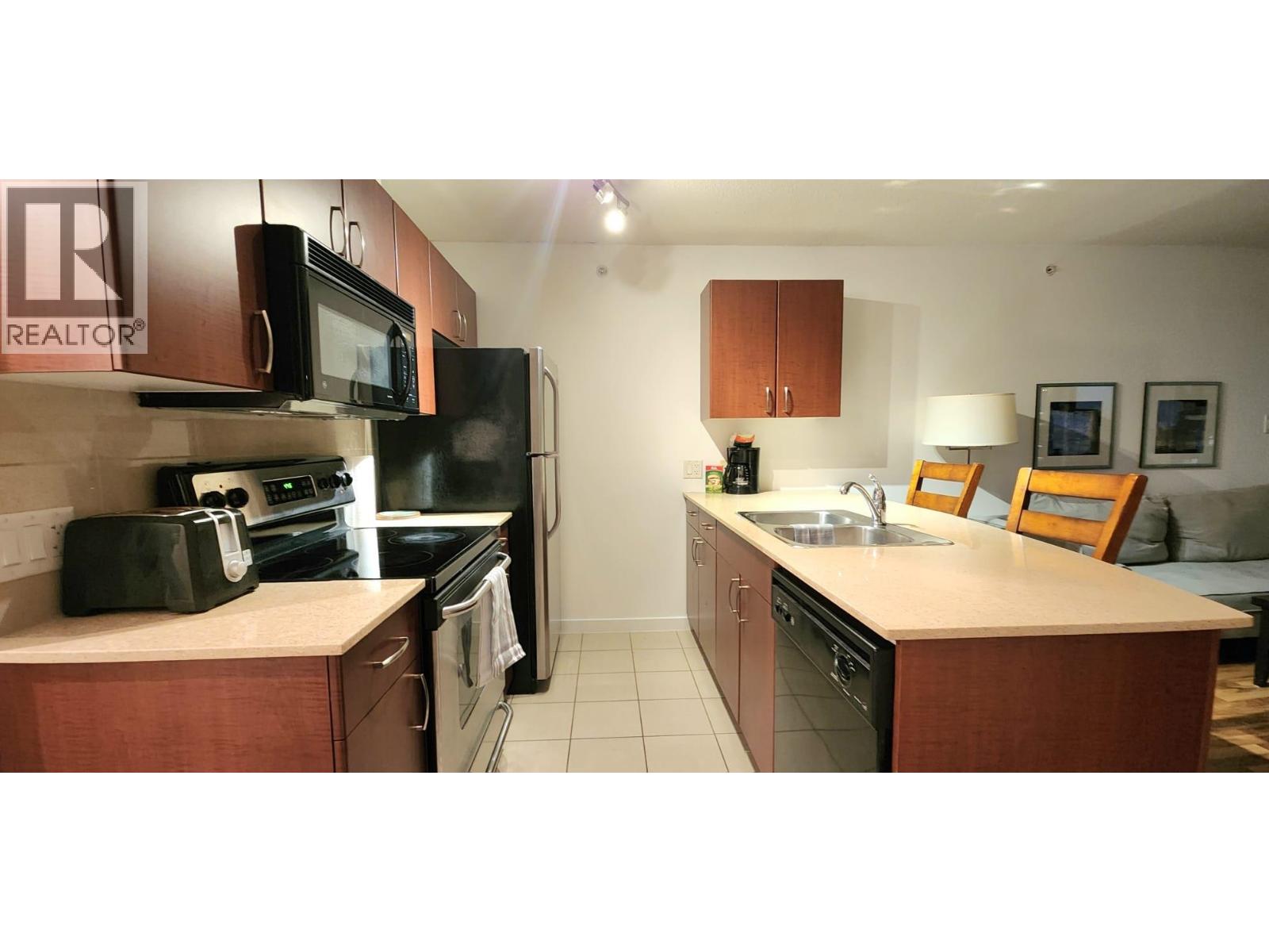 A kitchen with a sink, microwave, oven and fridge.