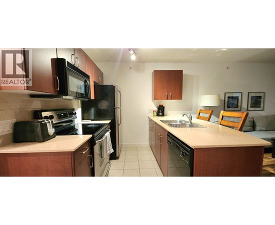 A kitchen with a sink, microwave, oven and fridge.