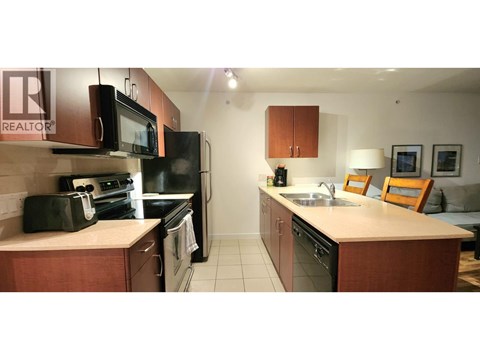 A kitchen with a sink, microwave, oven and fridge.