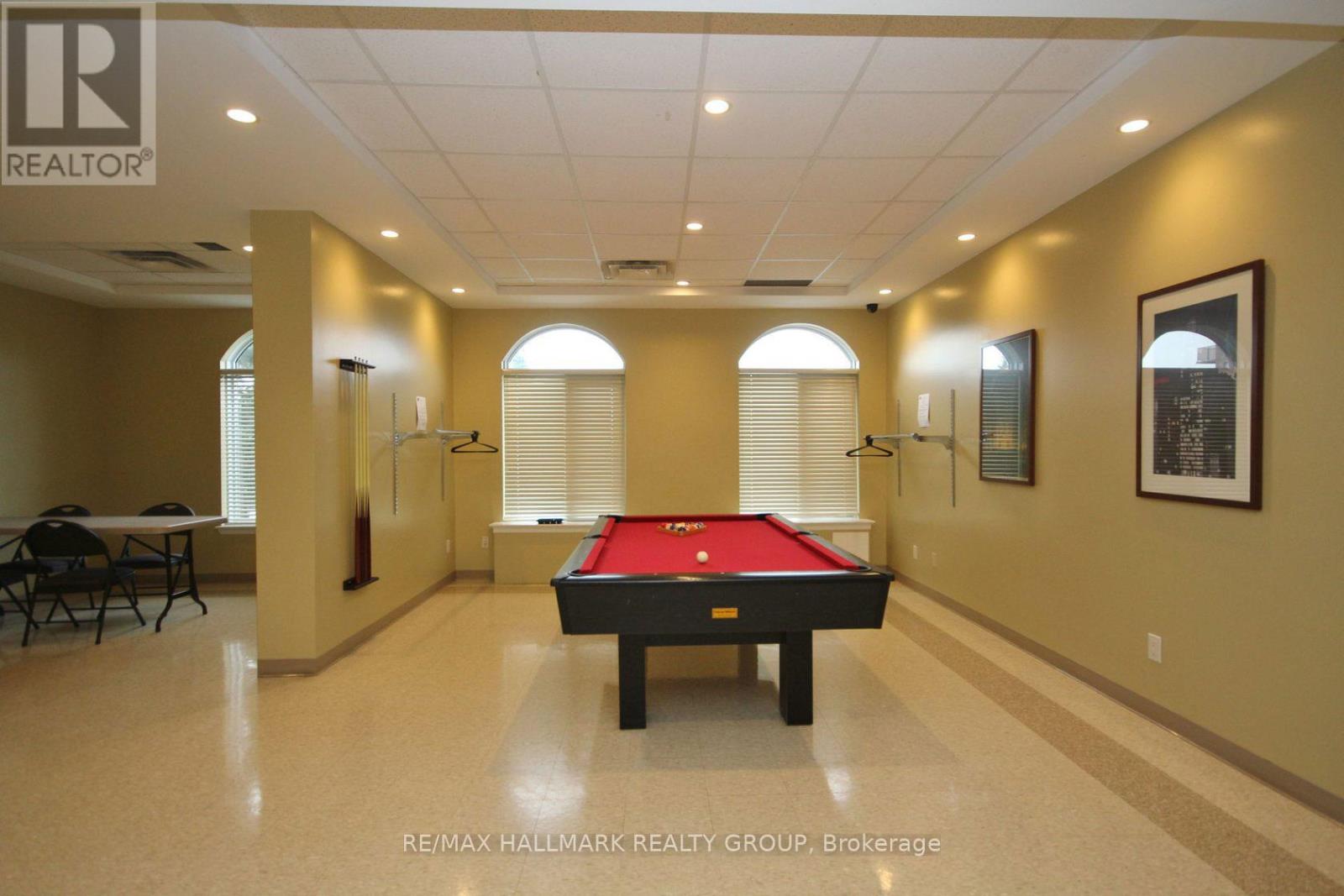 A pool table is in the middle of a room with a high ceiling.