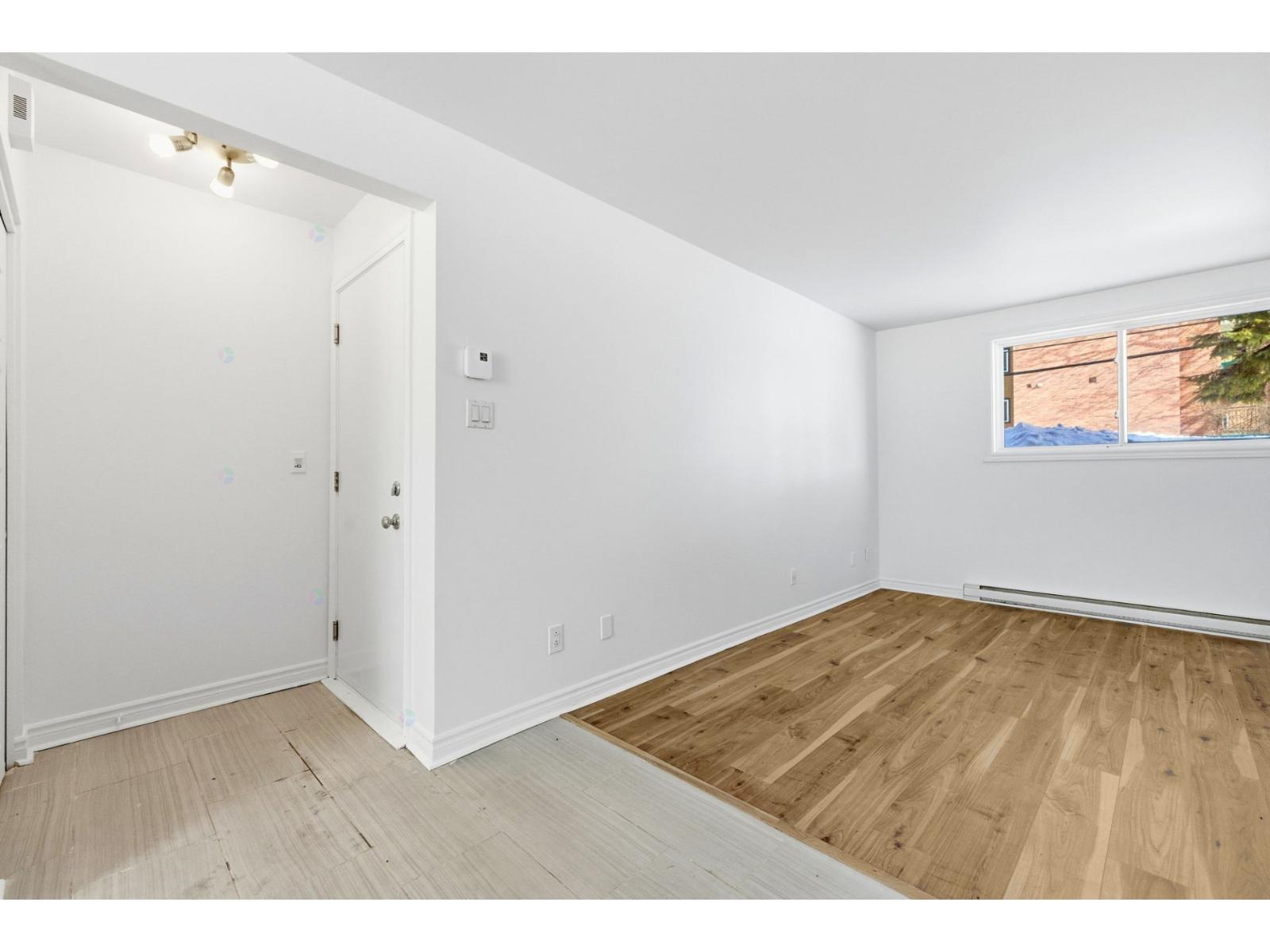 A room with a white door and a window with a view of a building outside.