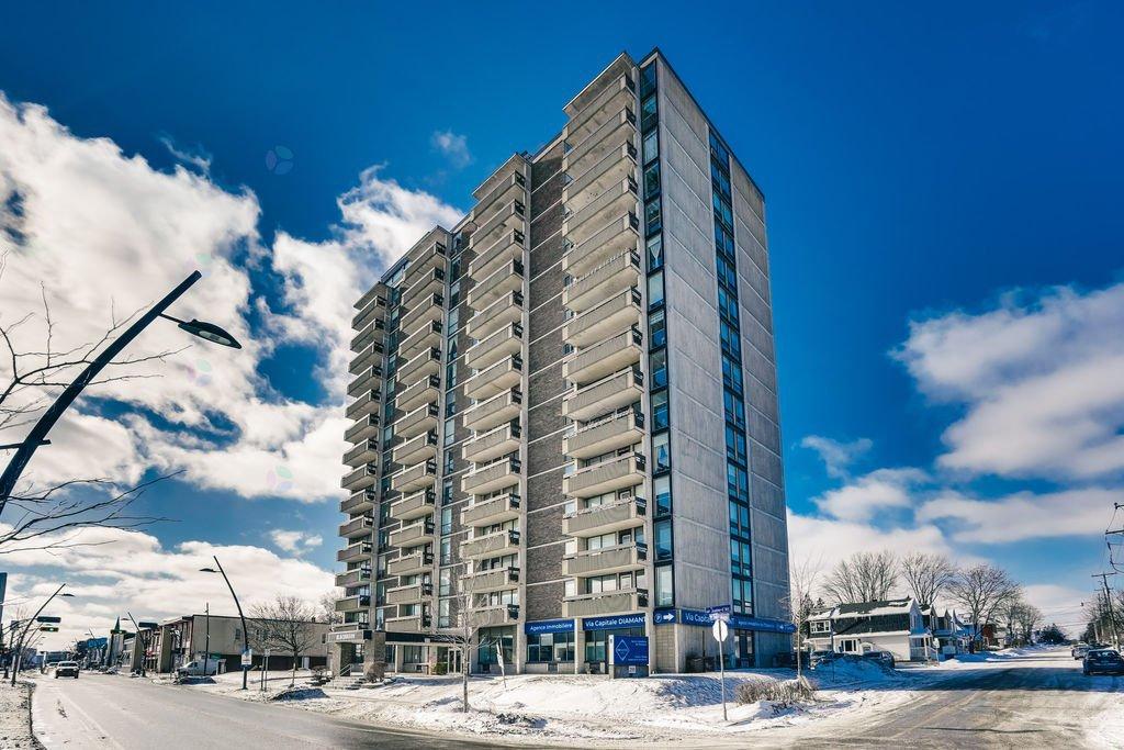 A tall residential building stands in the middle of a snowy street.